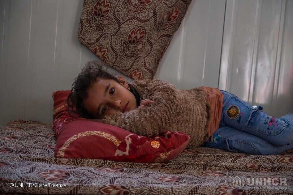 Seven-year-old Retaj AlMaslamani lays on a mattress on the ground inside a shelter in Zaatari refugee camp in Jordan. Her grandmother Ghasiba, 57, cares for her and her two younger sisters since their parents are divorced. When it rains the shelter leaks, and her grandmother struggles to keep them warm and dry.